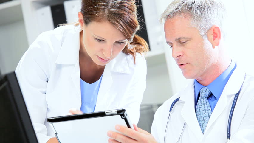 Caucasian doctors looking wireless tablet information clinic office