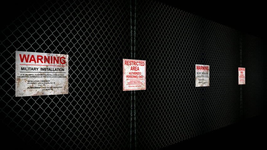 Restricted Area Sign. Two signs on a chain link fence notifying of a restricted area on a military installation. Camera goes past both signs and comes back out to a view of both.