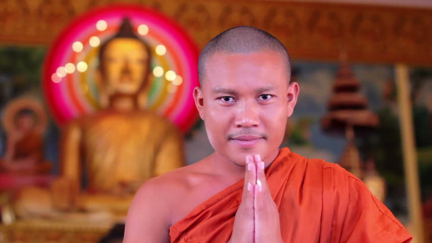 Center shot of Buddhist monk with orange robe pray in temple