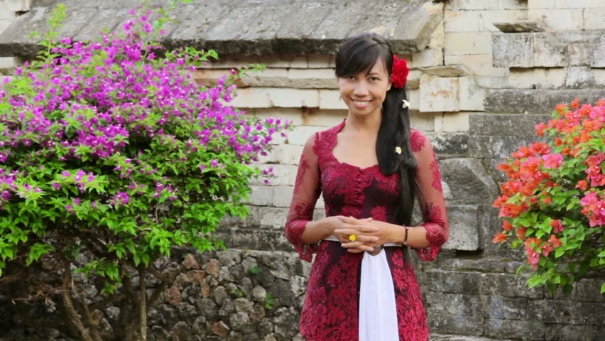 A pretty Balinese girl saluting with both hand in uluwatu temple, Bali