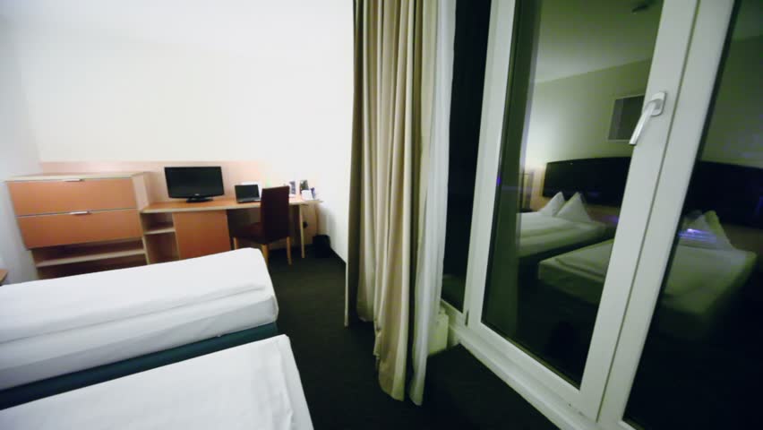 Hotel room with beds and computer on table, panoramic motion