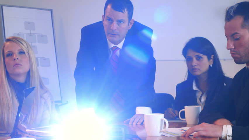 A group of young professionals discuss what they see projected on a screen off camera. Canon C300