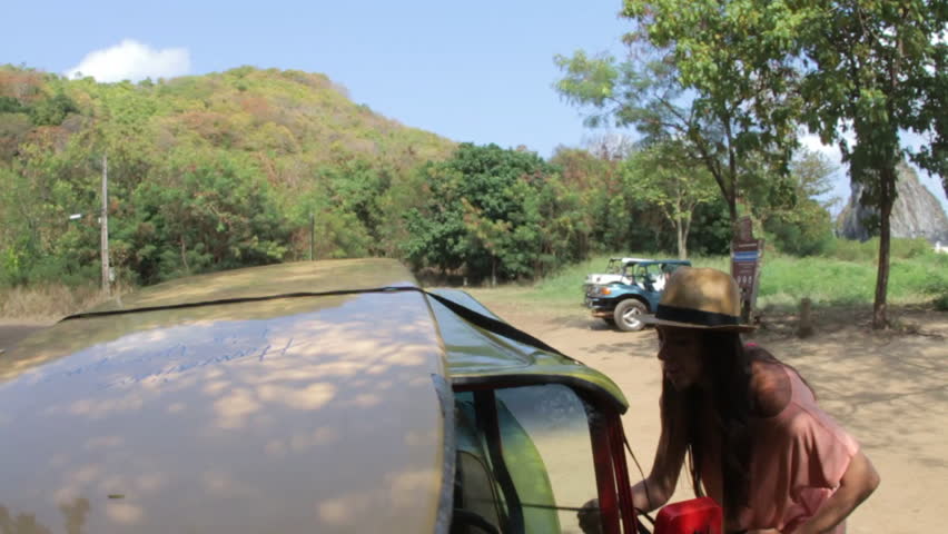 Woman untying surfboard from the top of the car