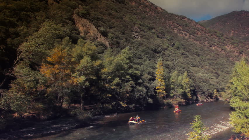 panomic view of a river in the Pyrenees (Catalonia-Spain) with rafting botes passing. Warm colors. 
