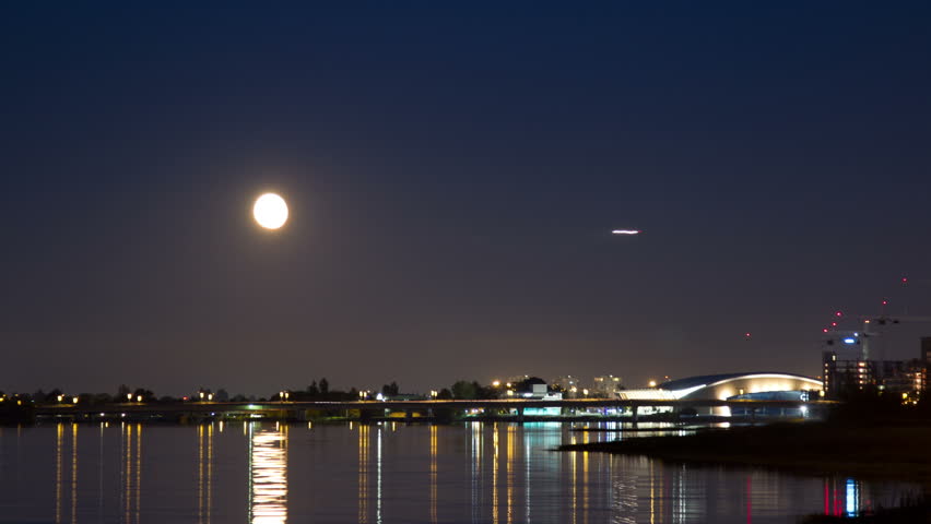 Moon Rising above the Richmond Olympic Oval in Richmond, BC, Canada. Airplane arriving to the Vancouver International Airport. Shot in 4k RAW photo sequence