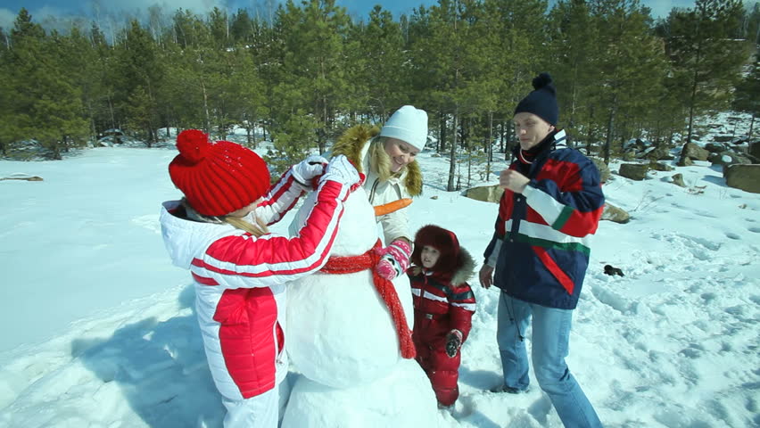 Cheerful family enjoying themselves on a winter day making a snowman