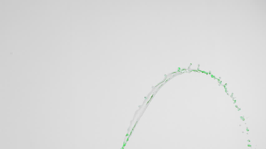 Green colored water in super slow motion rising against a grey background