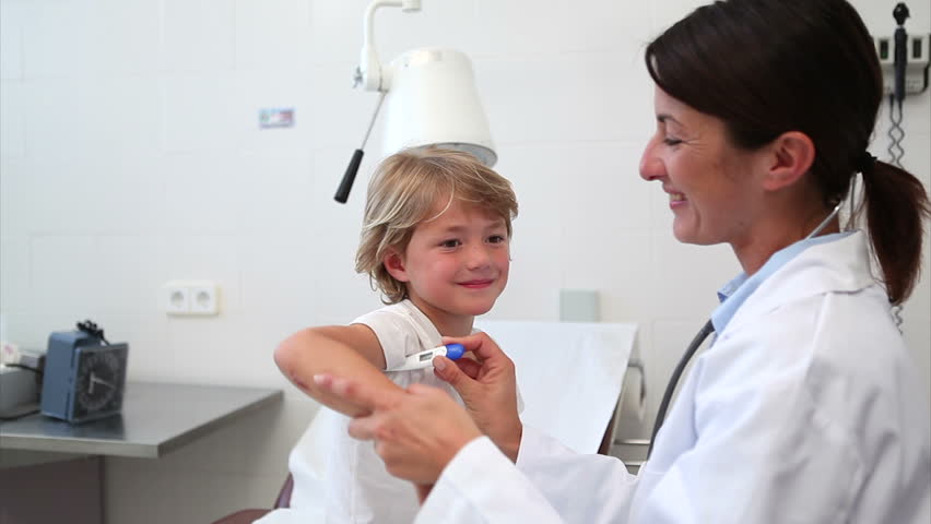 Doctor taking temperature of a child in examination room