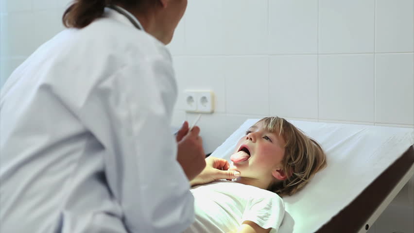Doctor auscultating the mouth of a child in an examination room