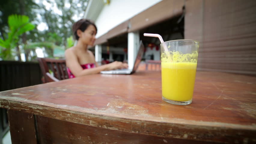 Freelance business woman working at cafe with a closeup of juice glass