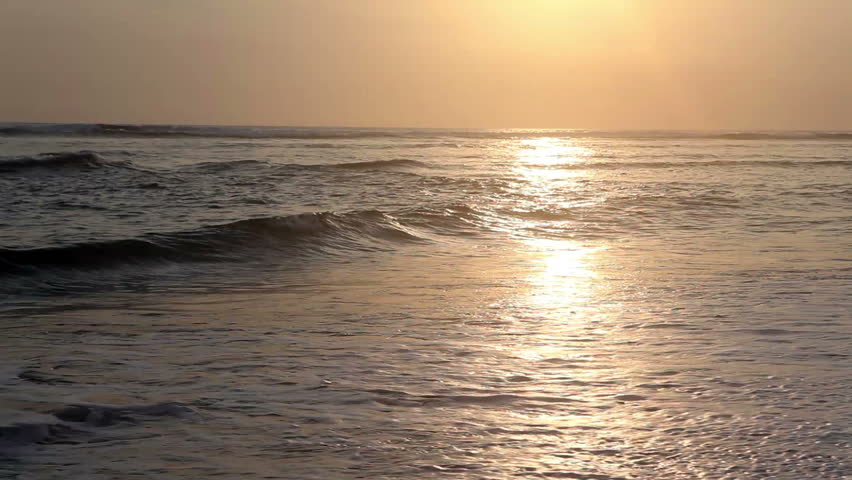 Surfer running into ocean and surfing while sunset