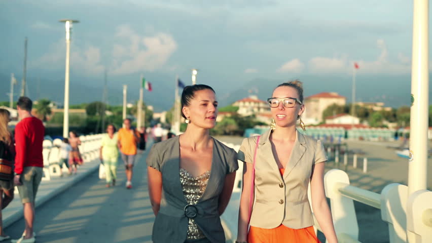 Two ladies walking along the pier, steadycam shot
