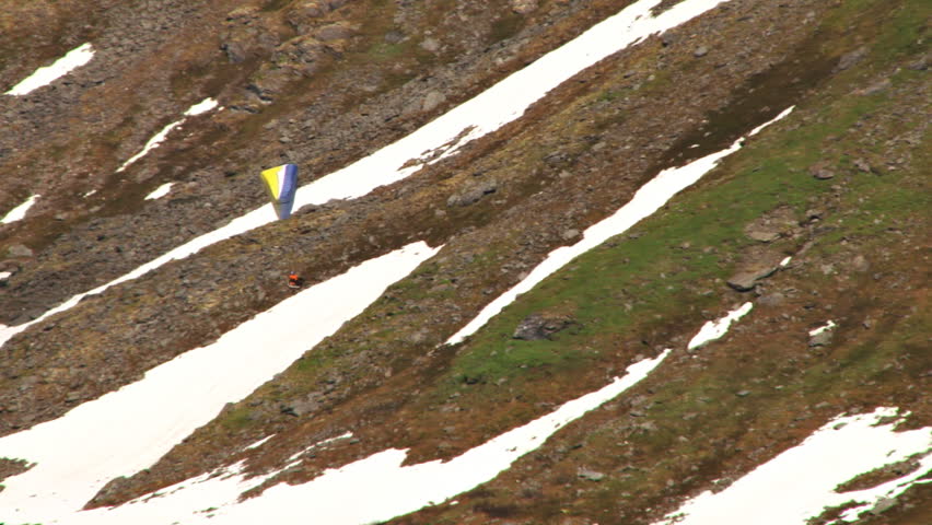 Paraglider gliding smoothly past a steep mountain slope makes a turn at Hatcher Pass in Alaska.