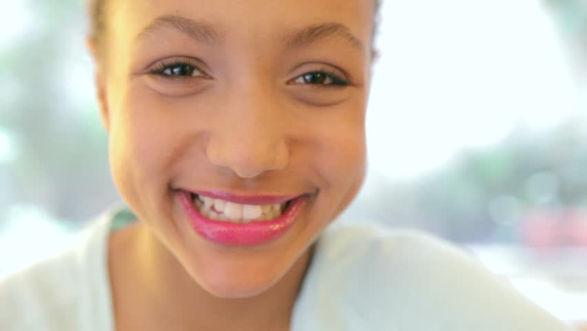 Close up portrait of a young child girl smiling at the camera. Out of focus image clears into focus as the girl smiles.