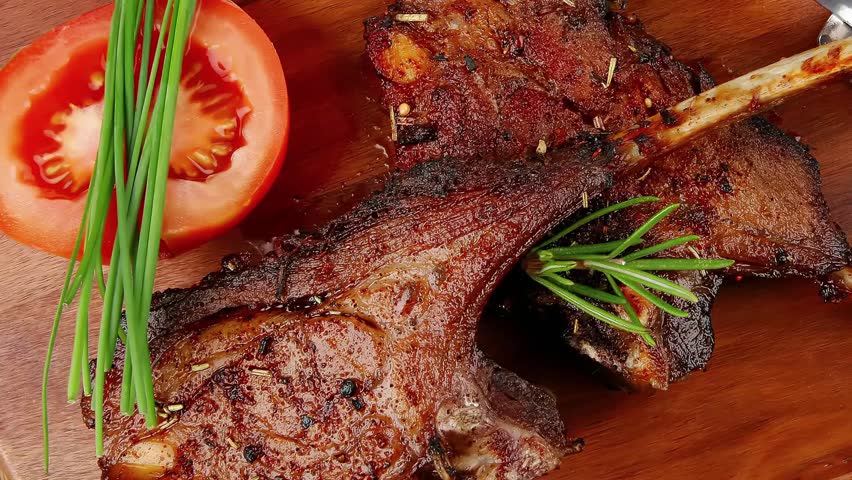 meat over wood: grilled ribs on plate with tomatoes and spices on wooden table