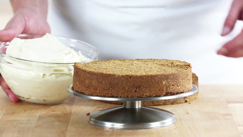 A cake base being spread with cream cheese