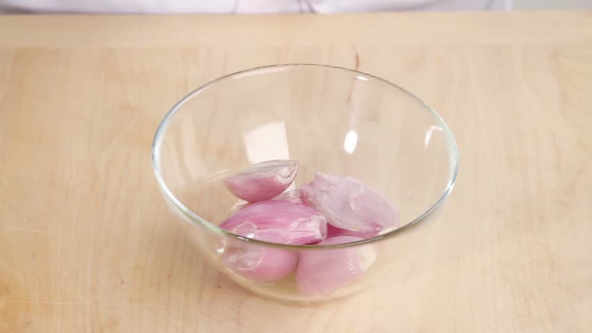 Shallots being sprinkled with rosemary needles