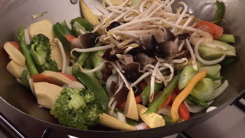 Mixing sprouts with vegetables in a wok