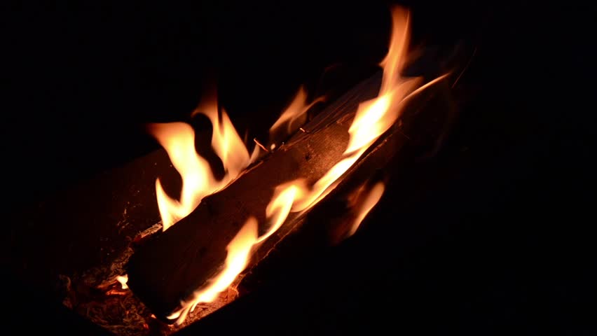 Fire burning in outdoor pit at night.