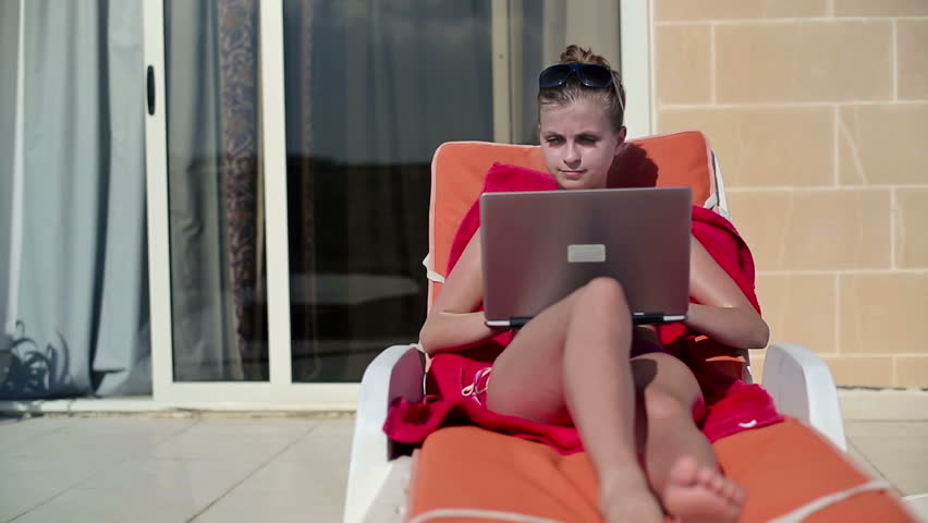 Beautiful woman with laptop on sunbed
