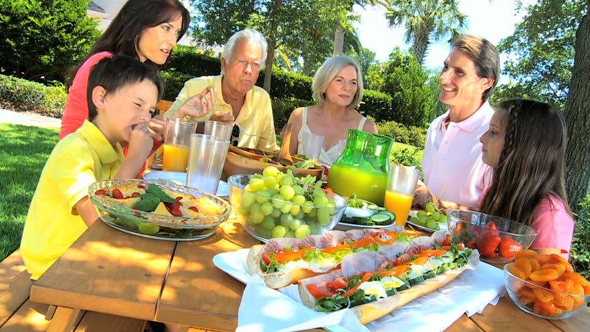 Grandparents sharing a healthy lunch outdoors with their family