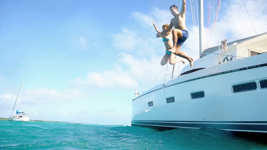 Young couple jumping in water from yacht