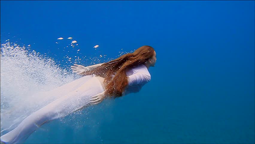 a girl dives into the sea fully clothed
