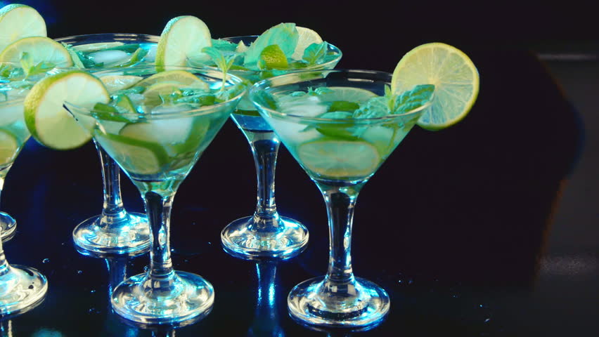 Martini cocktail with lime and mint on black background