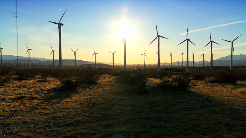 Wind turbines producing clean alternative energy in silhouette at dusk