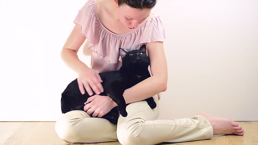 Young woman caress her big black calm cat at home