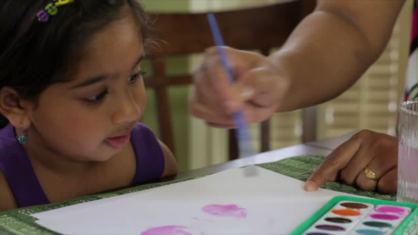 A loving Indian mother gives her pretty little girl pointers on how to use the water color paint.