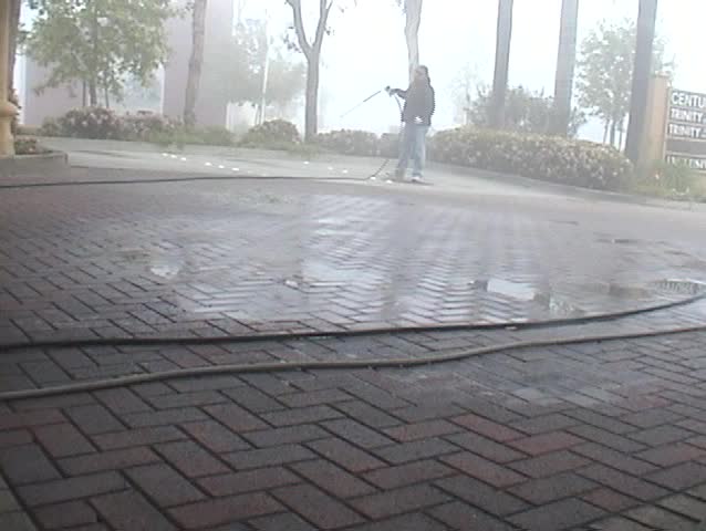 an unidentifiable person shows how to expertly power wash or Steam Clean a parking lot