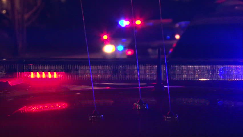 Police lights flashing at night downtown at crime scene.