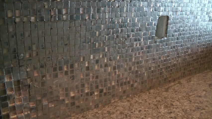 Tile worker spread grout over mini decorative tiles as a back splash for new apartment construction.