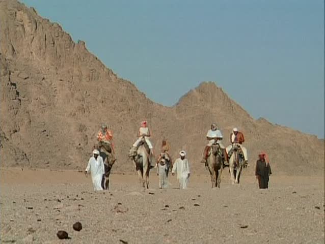 Egyptian people walking through the desert and riding a camel