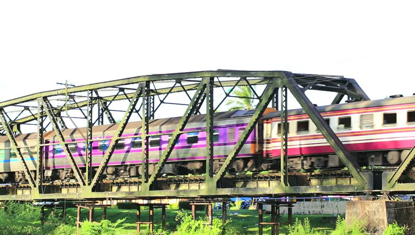 Passenger train passes a bridge in countryside of Thailand