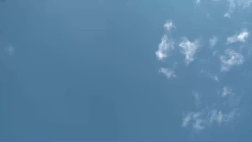 Colorful football being thrown straight up towards blue sky and then returning downward, and done again.