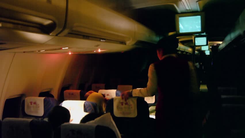 URUMCHI - NOV 28: Stewardess switches light in dark cabin of aircraft with passengers on Nov 28, 2011, in Urumchi, China.