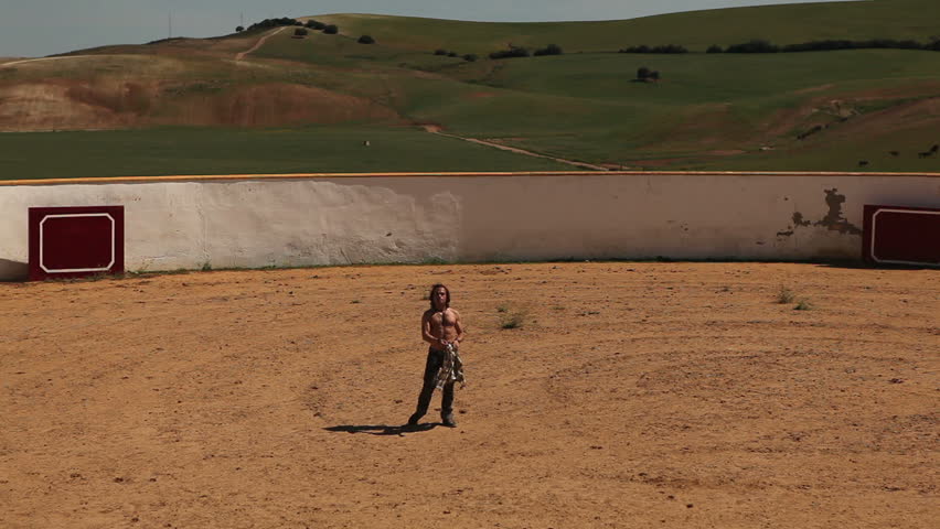 Man training as bullfighter in empty arena in a sunny day