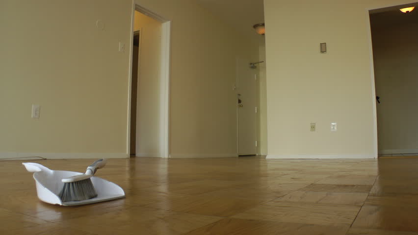 Empty room in apartment awaiting rental, camera dollies.  No furniture, only dustpan on parquet wood floor. Housing market recovering? or eviction.