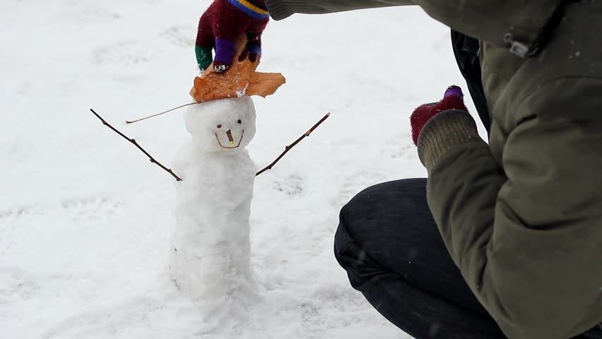 Man building a tiny snowman