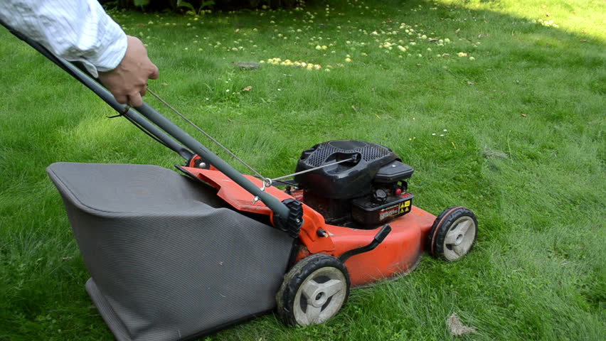 man gardener worker start grass lawn cutter mower on meadow.