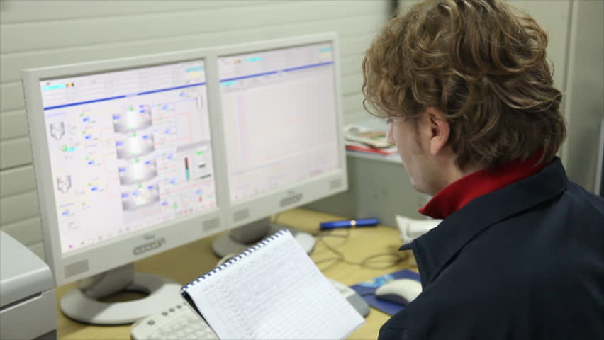 The worker writes the results of measuring devices in the control room at the factory