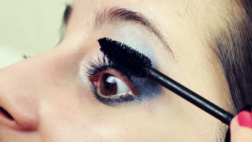 beautiful young woman brushing her eyelashes