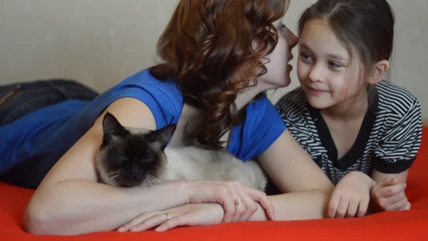 mother and daughter having fun talking with cat 