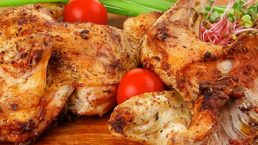 meat food : roasted chicken legs garnished with green sprouts and peppers on wooden plate hidef slow motion intro