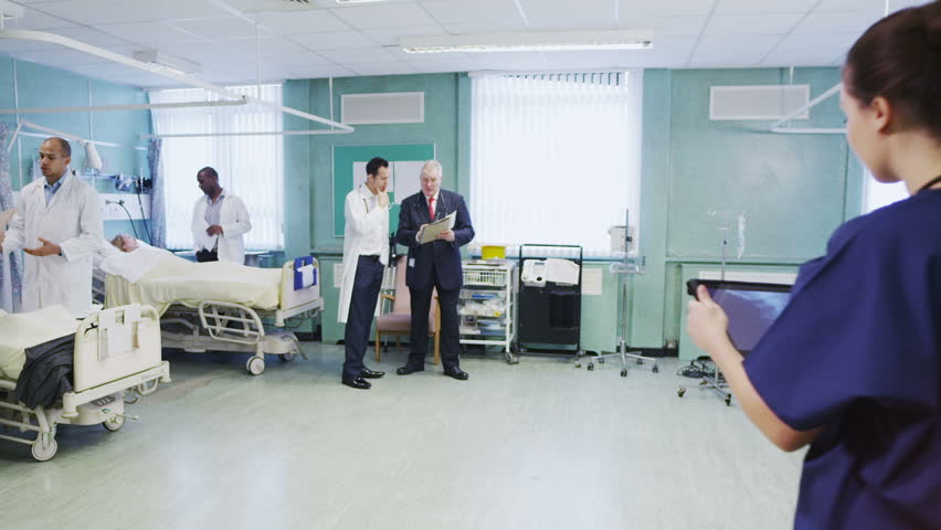 Hospital staff are doing their rounds and a young medical assistant takes a patient's x-ray results to the doctor. 