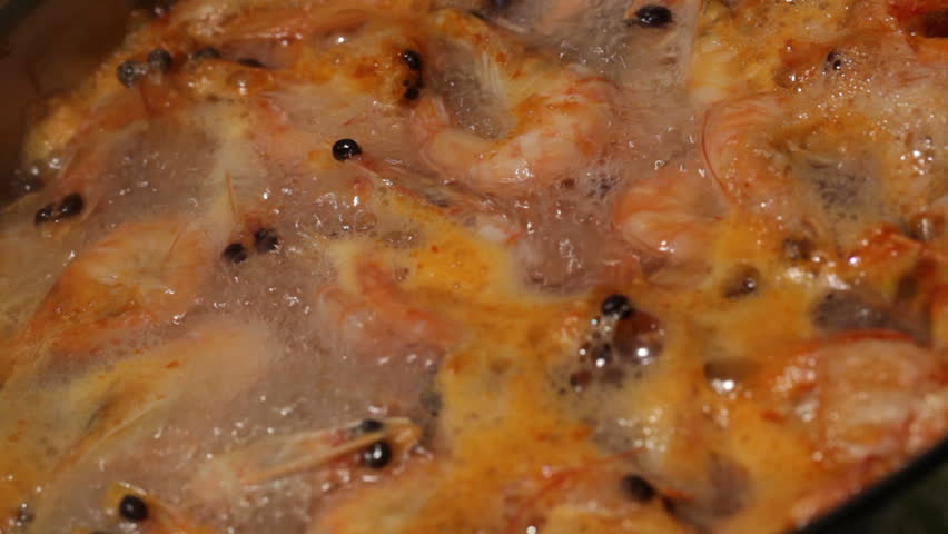 Background. Shrimp are simmered in a saucepan.