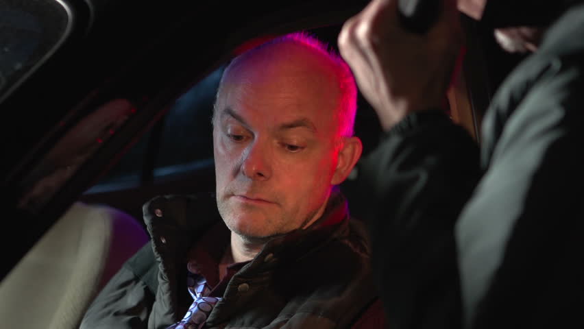 Man being pulled over by a police officer with flashing lights