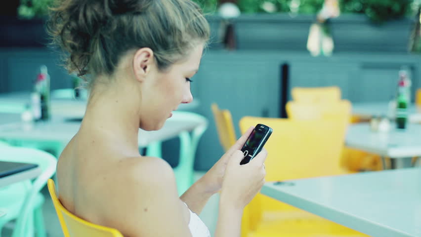 Beautiful woman texting message on mobilephone in the restaurant, steadycam shot
